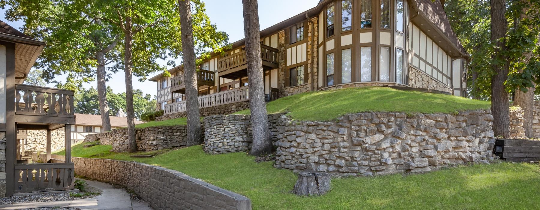 an apartment with a stone wall and trees in front of it