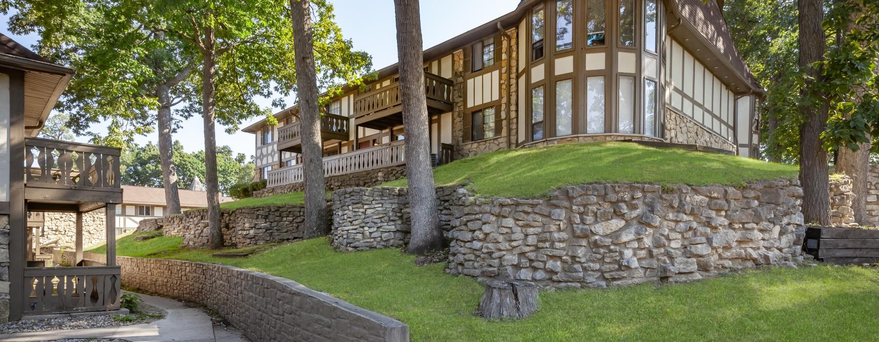 an apartment with a stone wall and trees in front of it